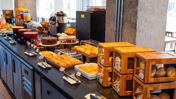 Buffet com diversos alimentos e uma máquina de café.