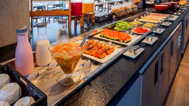 A buffet with various food items and beverages, including a tropical drink and sliced fruits. - ibis budget Porto Alegre - Supereconômico (Porto Alegre)