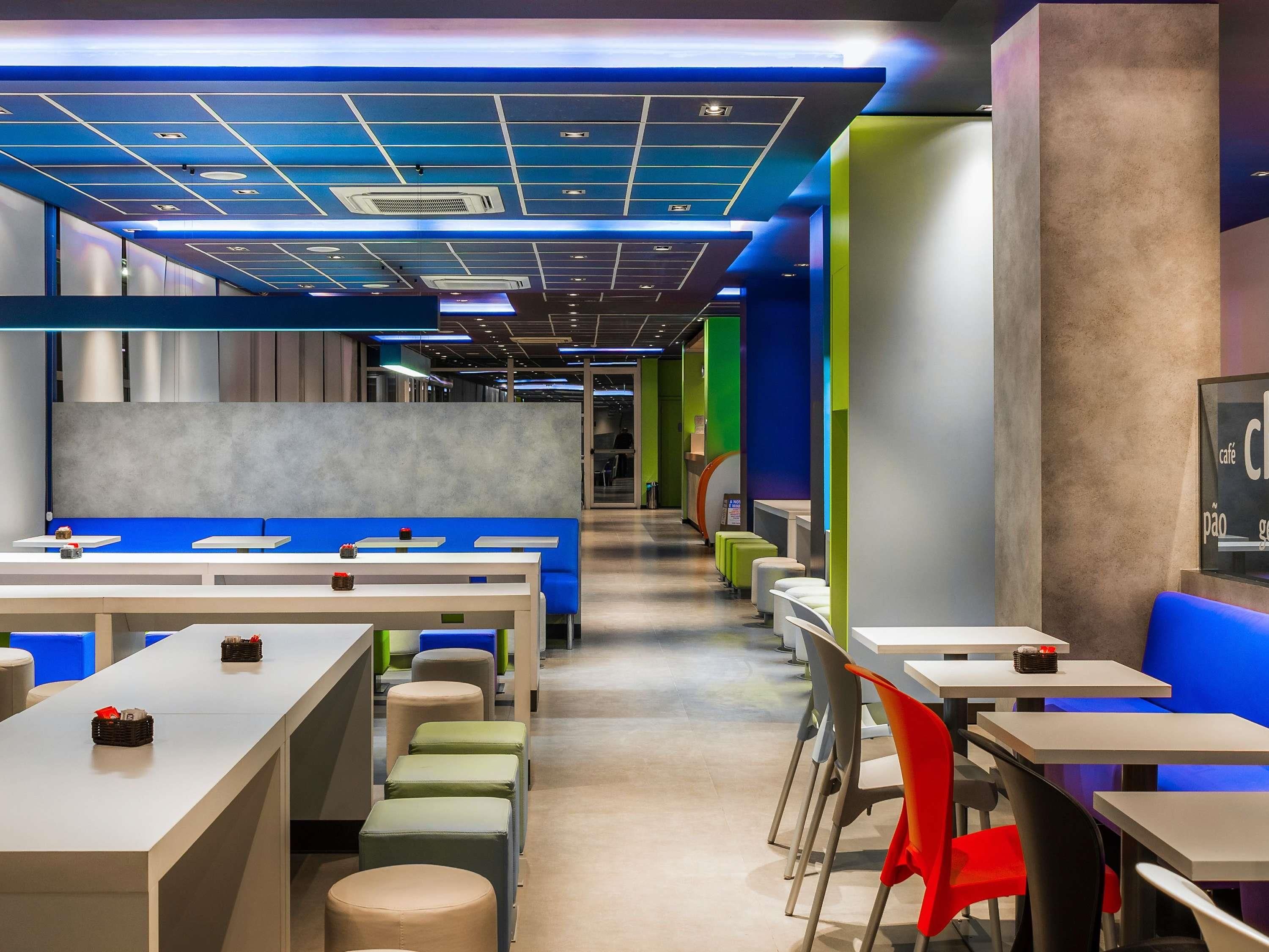 Un café moderne doté de plusieurs espaces de détente, comprenant des tables et des chaises, et dont le menu est affiché de manière visible.