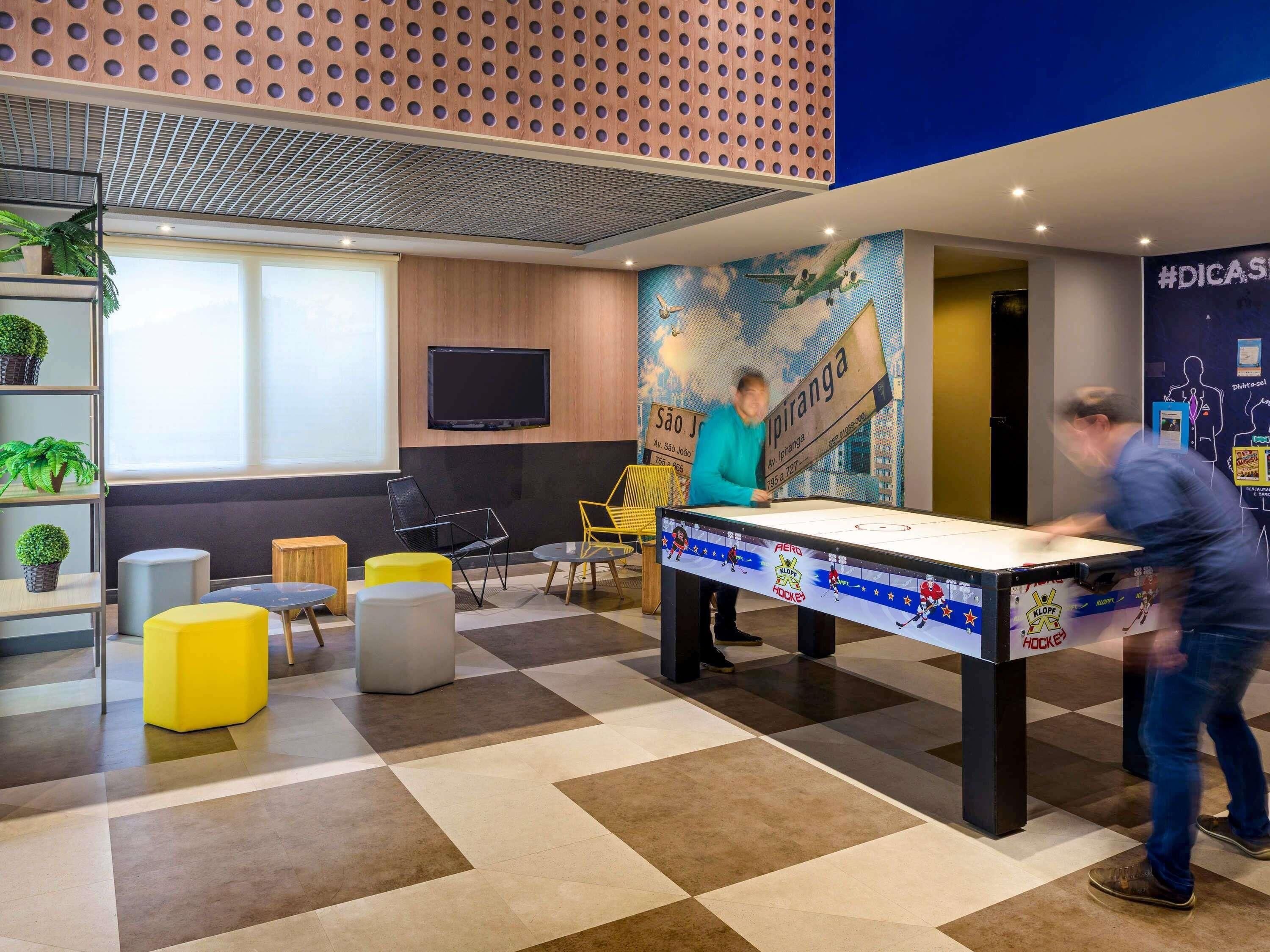 A modern indoor space with a foosball table, seating areas, and a mural.