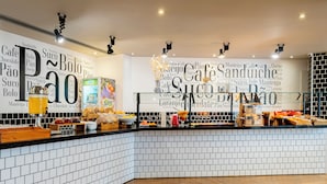 A cafe with a white tiled wall featuring words like "Cafe," "Sandwich," and "Bolo." - Ibis Budget SP Centro São João (São Paulo)