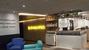 A modern interior with a neon sign reading "EVANDORES," a counter with a tiled backsplash, and seating areas with blue chairs. - Ibis Budget SP Centro São João (São Paulo)