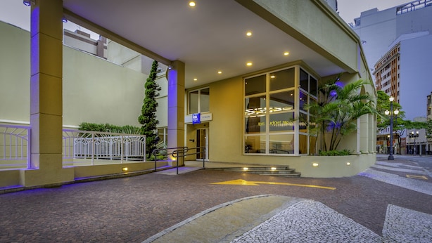A hotel entrance with a modern design, including a glass facade, a staircase leading to the entrance, and a well-lit pathway. - Ibis Budget SP Centro São João (São Paulo)