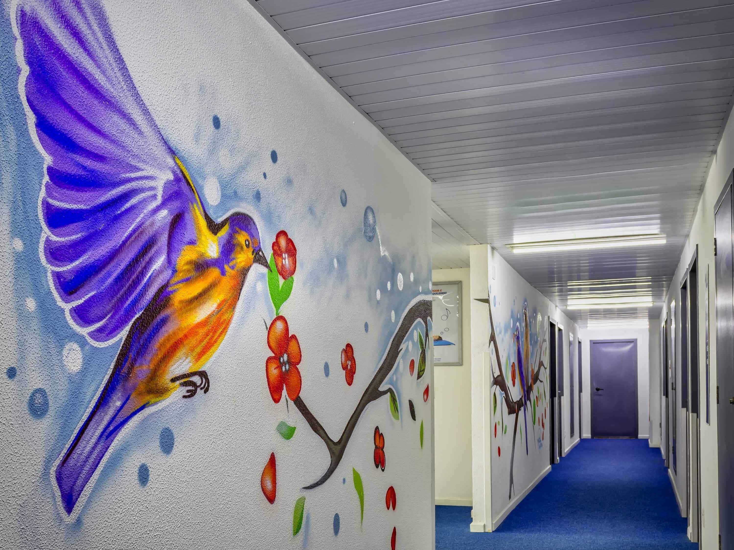 A hallway with a vibrant mural of a bird and flowers on the wall.
