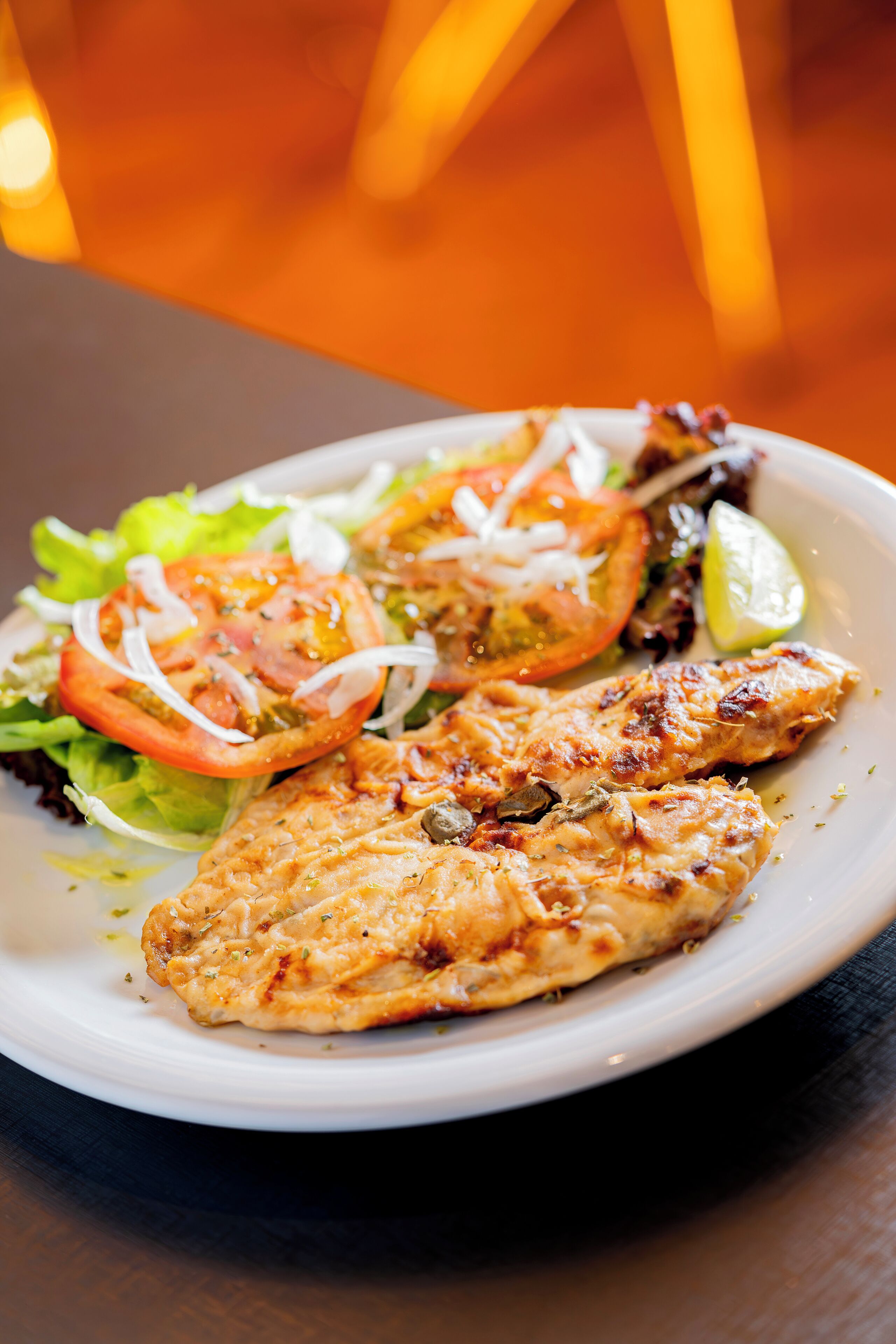 Un plato de pollo a la parrilla con una ensalada.
