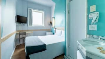 Une chambre d’hôtel équipée d’un lit, d’un bureau, d’une télévision et d’une salle de bain.