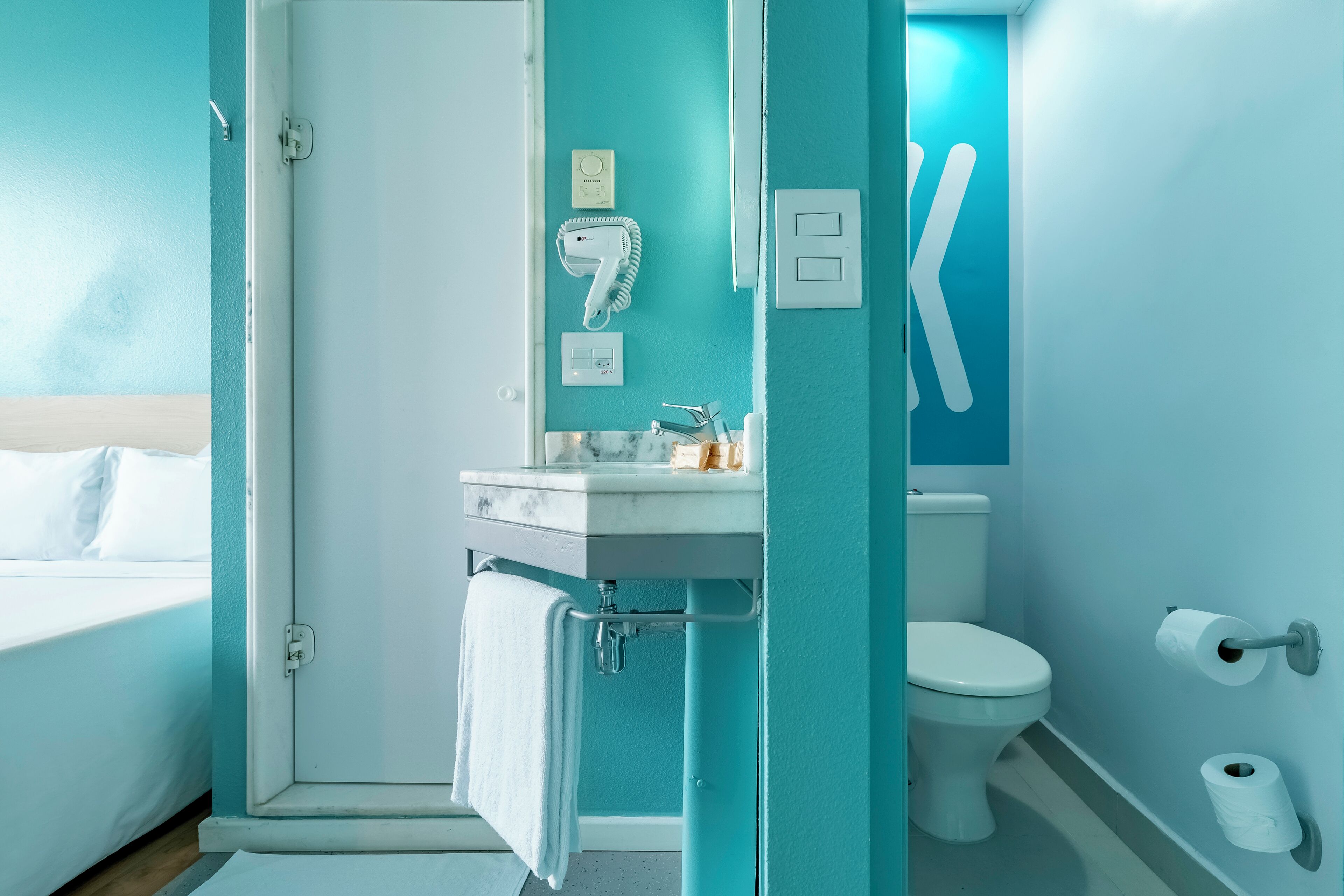 A bathroom with a sink, toilet, and a towel hanging on the door.