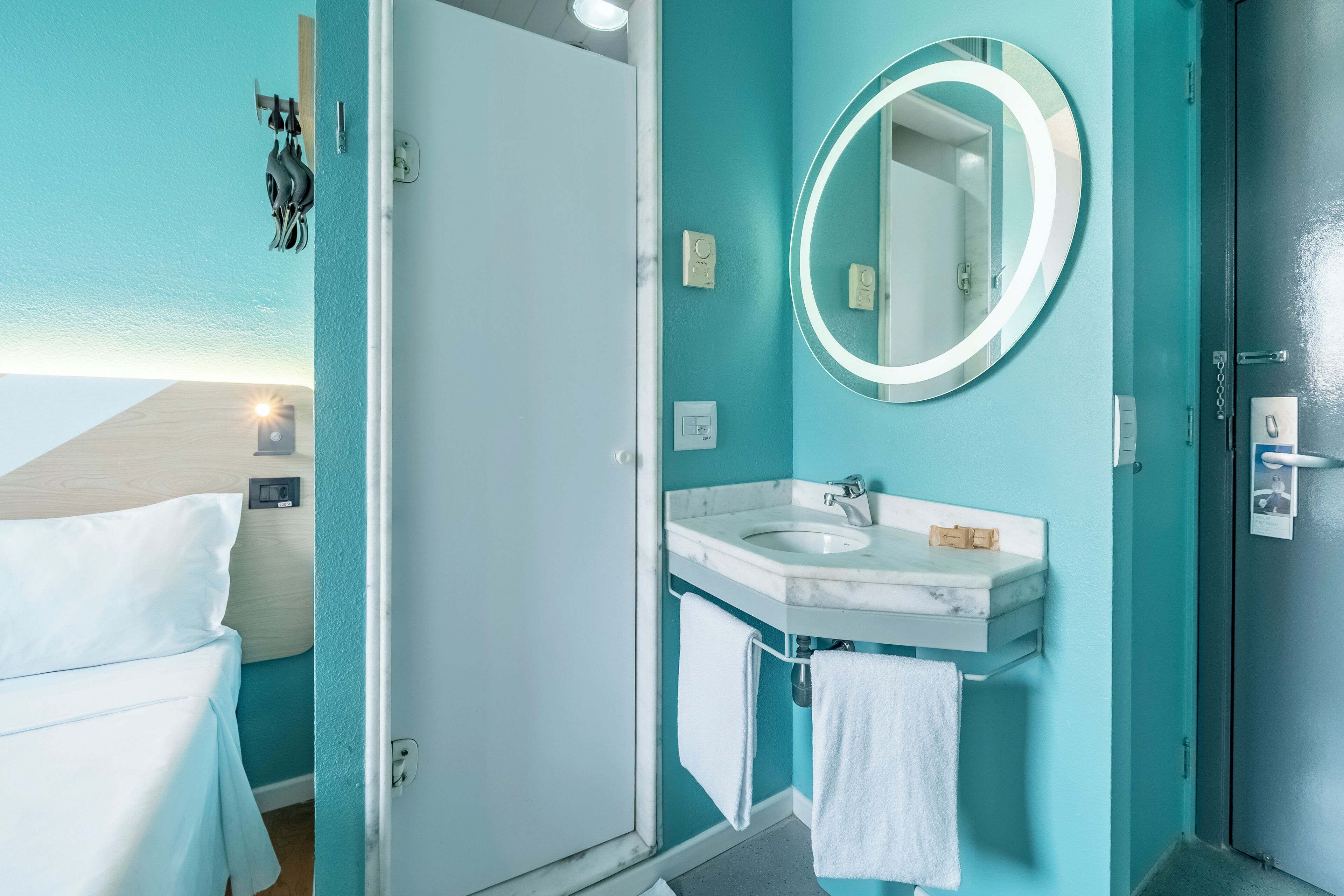 Un baño con lavamanos, espejo y toallero.