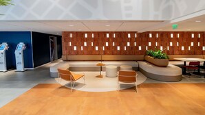 Eine moderne Lobby mit Sitzgelegenheit, einer Rezeption und einer Pflanze.