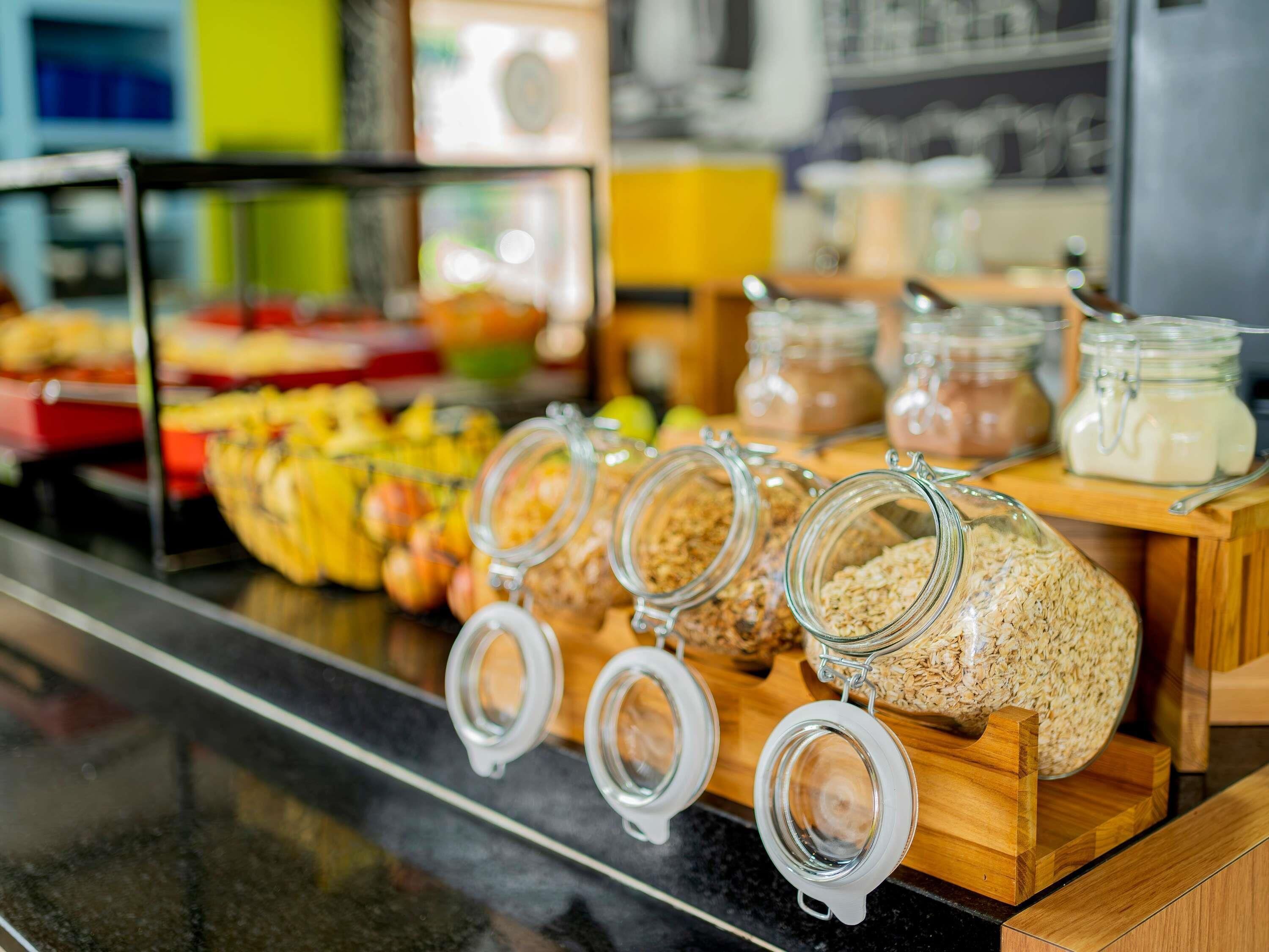 A breakfast buffet with various food items and jars of oatmeal and other grains.