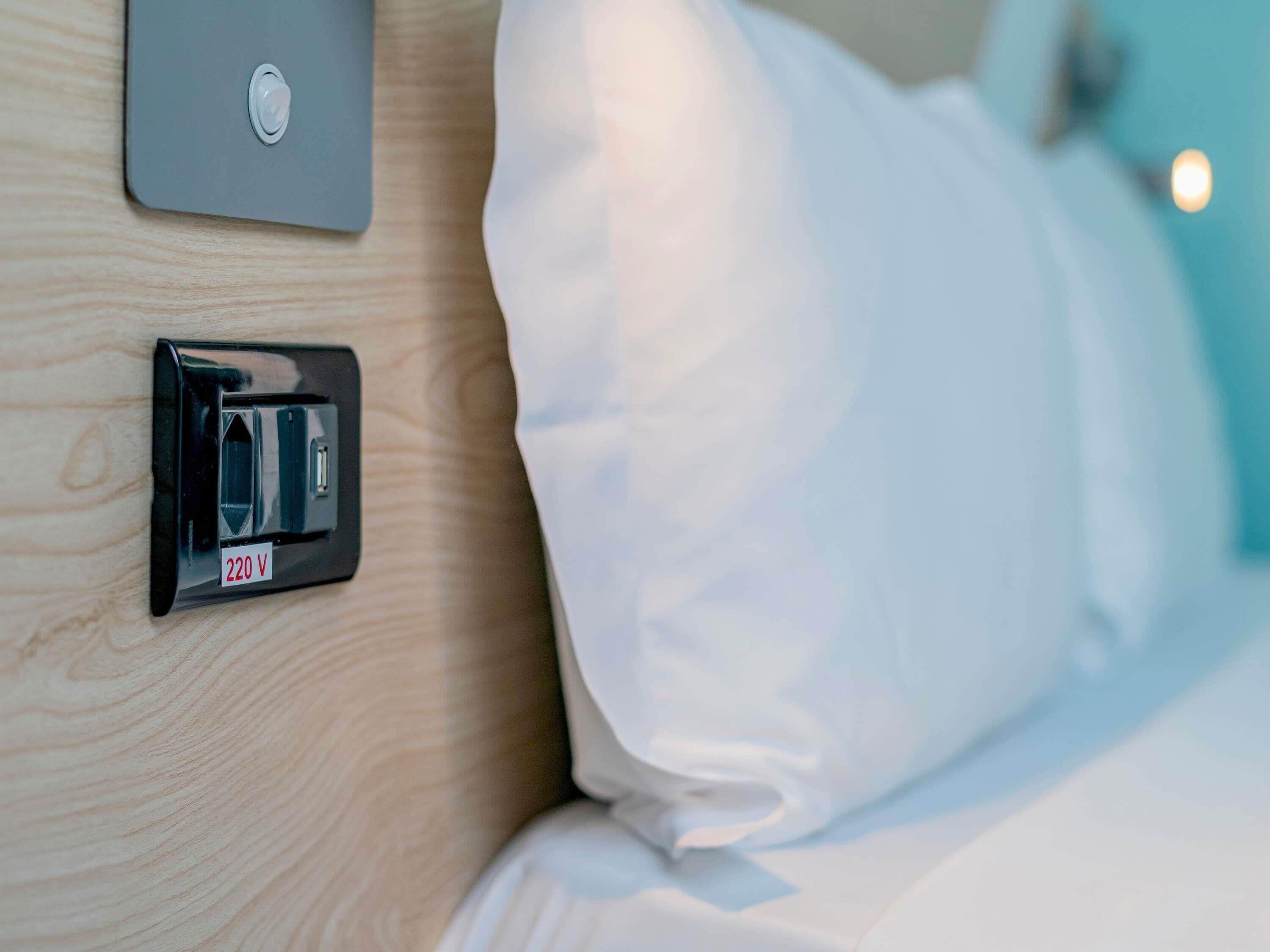 Habitación de hotel con mesita de noche, toma de corriente y puerto de carga USB.