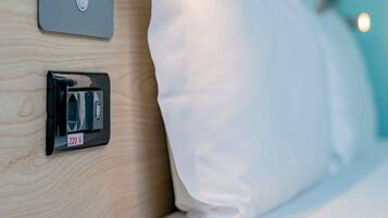 Habitación de hotel con mesita de noche, toma de corriente y puerto de carga USB.