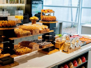 Un bufé con diversos productos de panadería y postres.