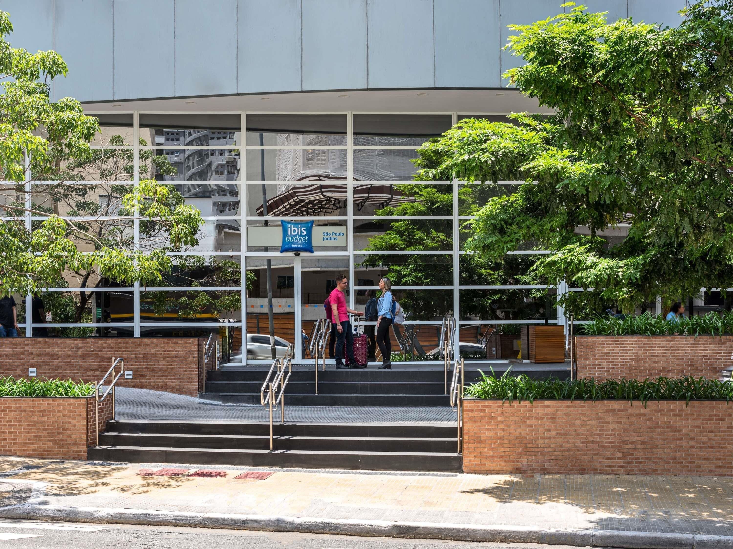 A hotel entrance with a sign for ibis budget, a staircase, and a view of the surrounding buildings.