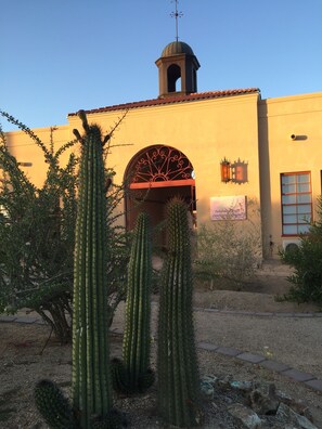 A building with a bell tower, a large arched entrance, and cacti in the foreground. - Sonoran Desert Inn & Conference Center (Ajo)
