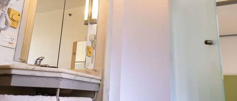 Un baño con espejo, toallero, secador de pelo y zona de ducha.