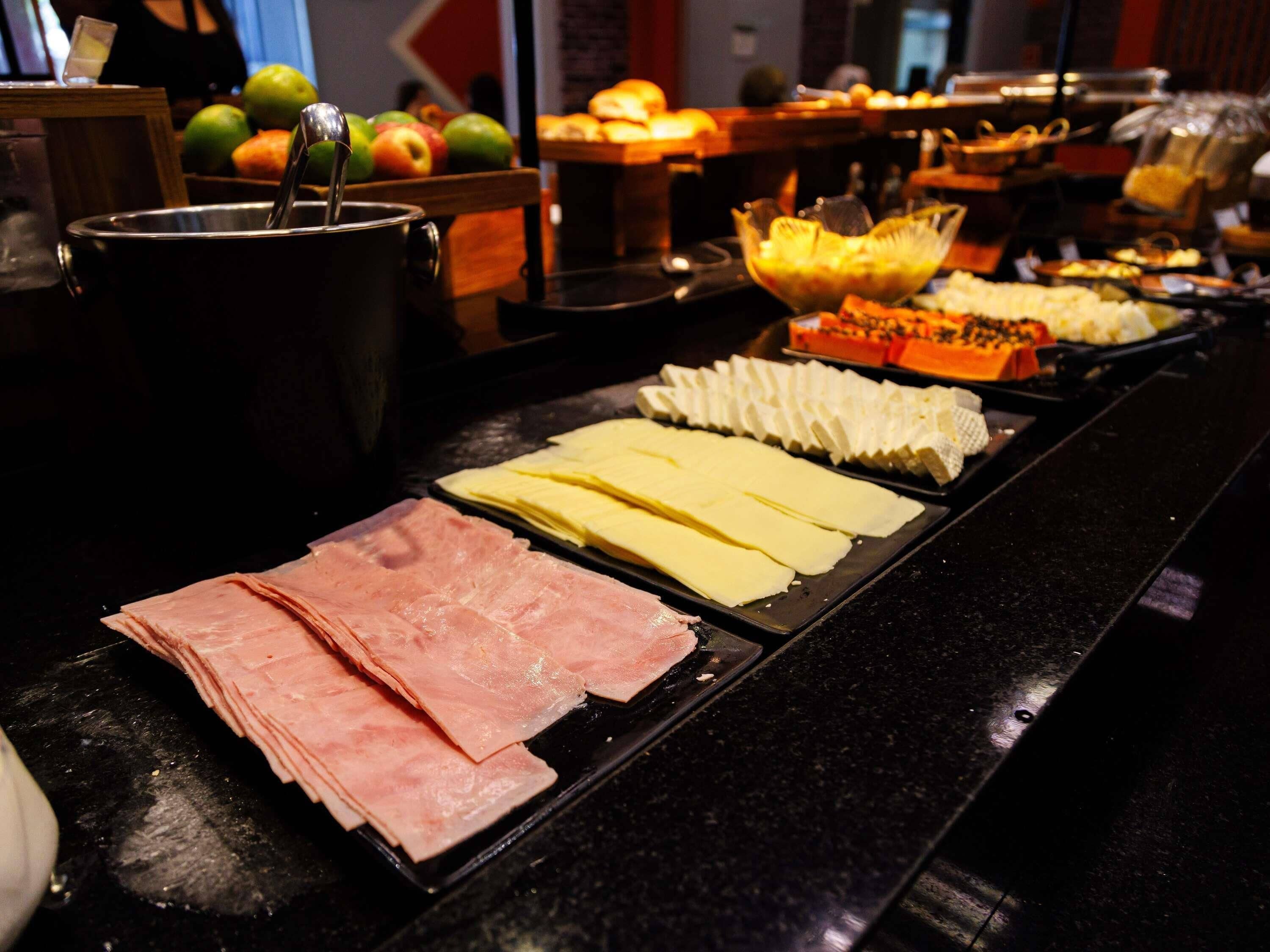 A buffet with various food items including meats, cheeses, and fruits.