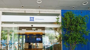 Ein moderner Hotel Eingang mit Glastüren, einer Rezeption und einem Blumentopf.