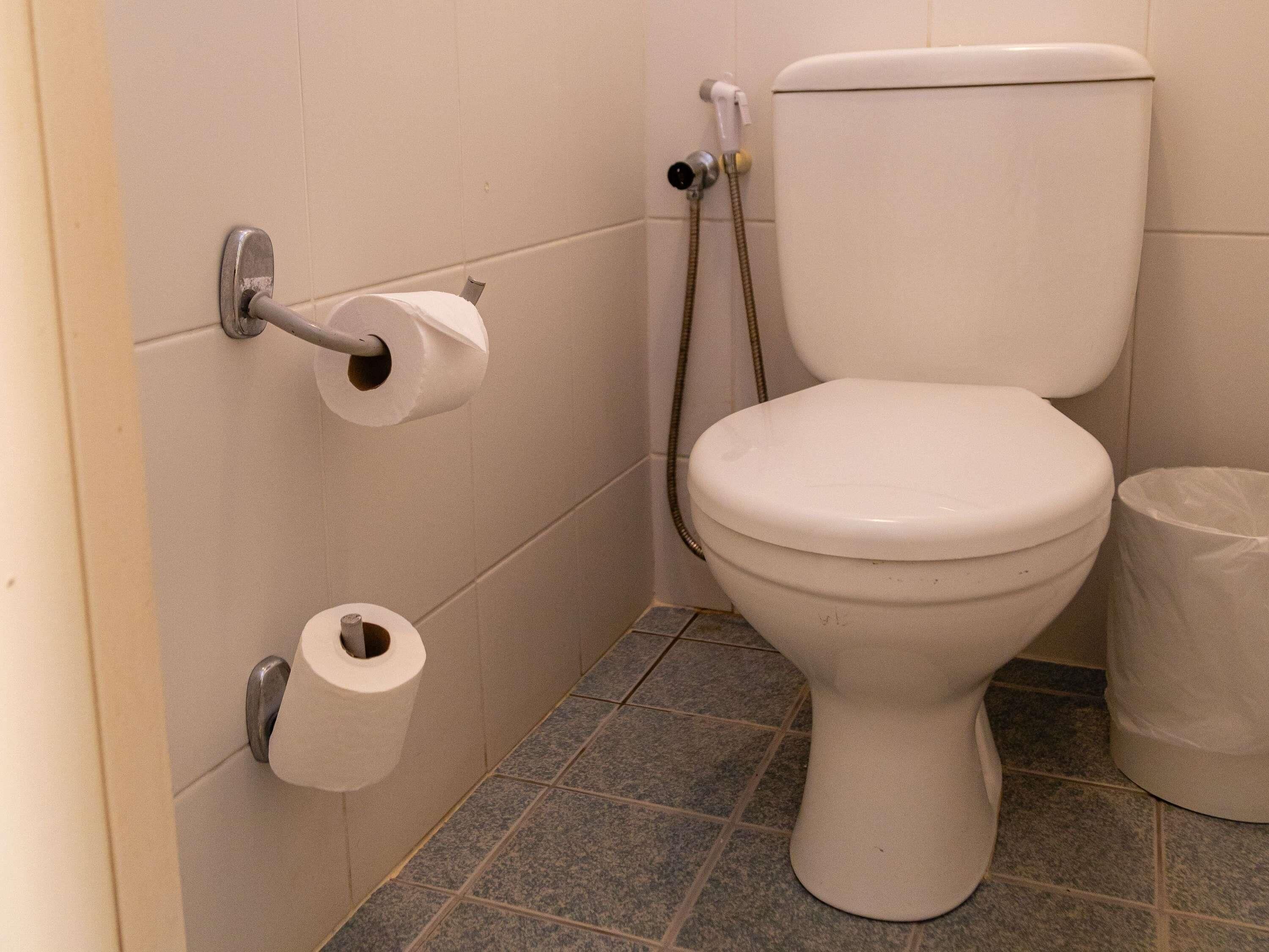 Des toilettes équipées d’un porte-serviettes en papier, d’un rouleau de papier toilette et d’un dispositif de bidet.