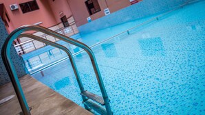 A swimming pool with a tiled floor and a metal ladder. - Les Ambassadeurs Appart Hotel (Marrakech)