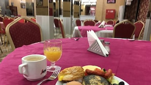 A breakfast setting with a plate of eggs, toast, and fruit, a glass of orange juice, and a coffee cup on a table with a pink tablecloth. - Les Ambassadeurs Appart Hotel (Marrakech)