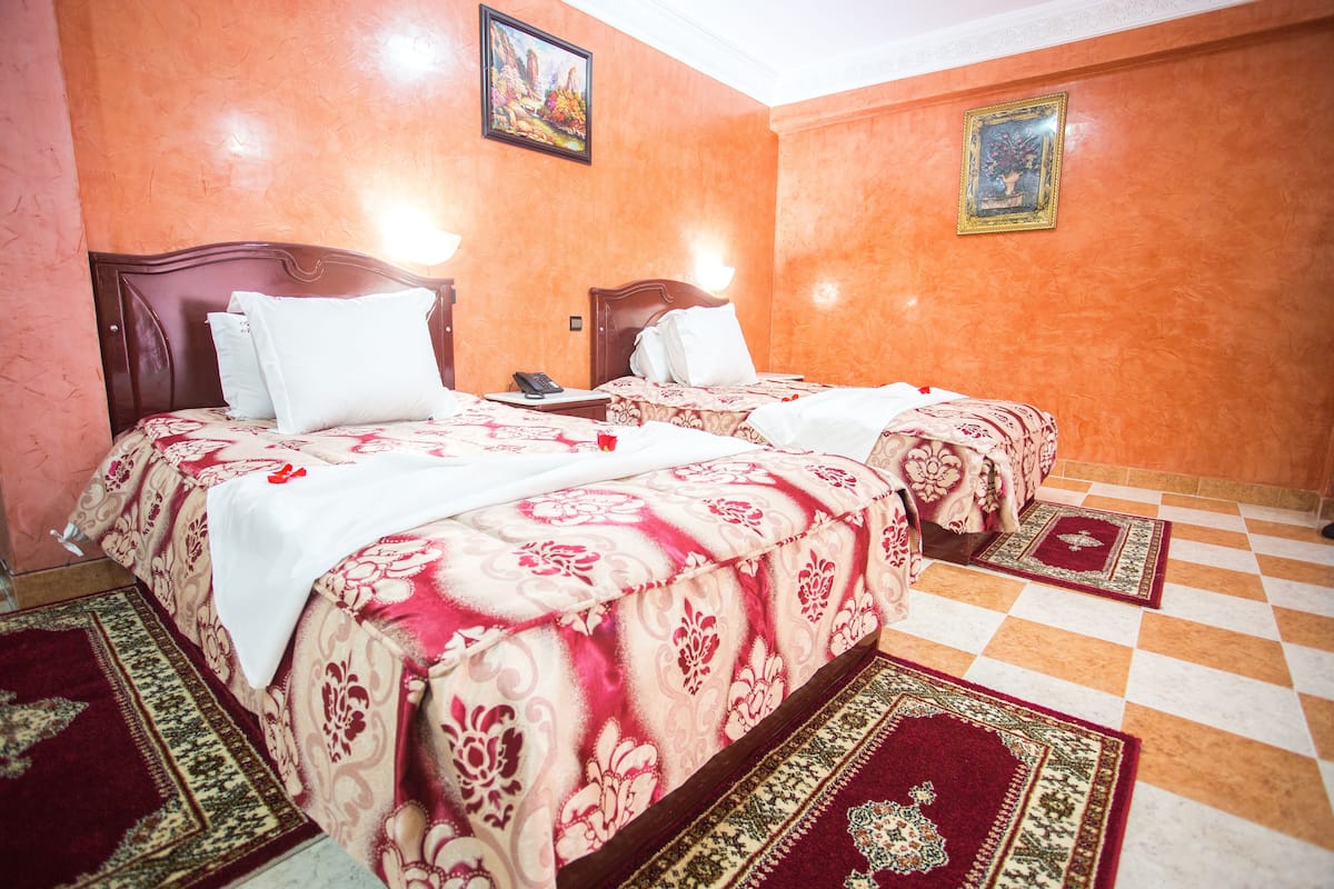 A hotel room with two beds, a checkered floor, and patterned carpets.