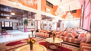 A spacious lobby with a red carpet, a sofa set, and a coffee table with a vase of flowers. - Les Ambassadeurs Appart Hotel (Marrakech)