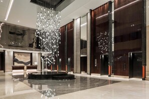 A modern lobby with a central chandelier, elevators, and a reception desk. - Hyatt Regency Shanghai Global Harbor (Shanghai)