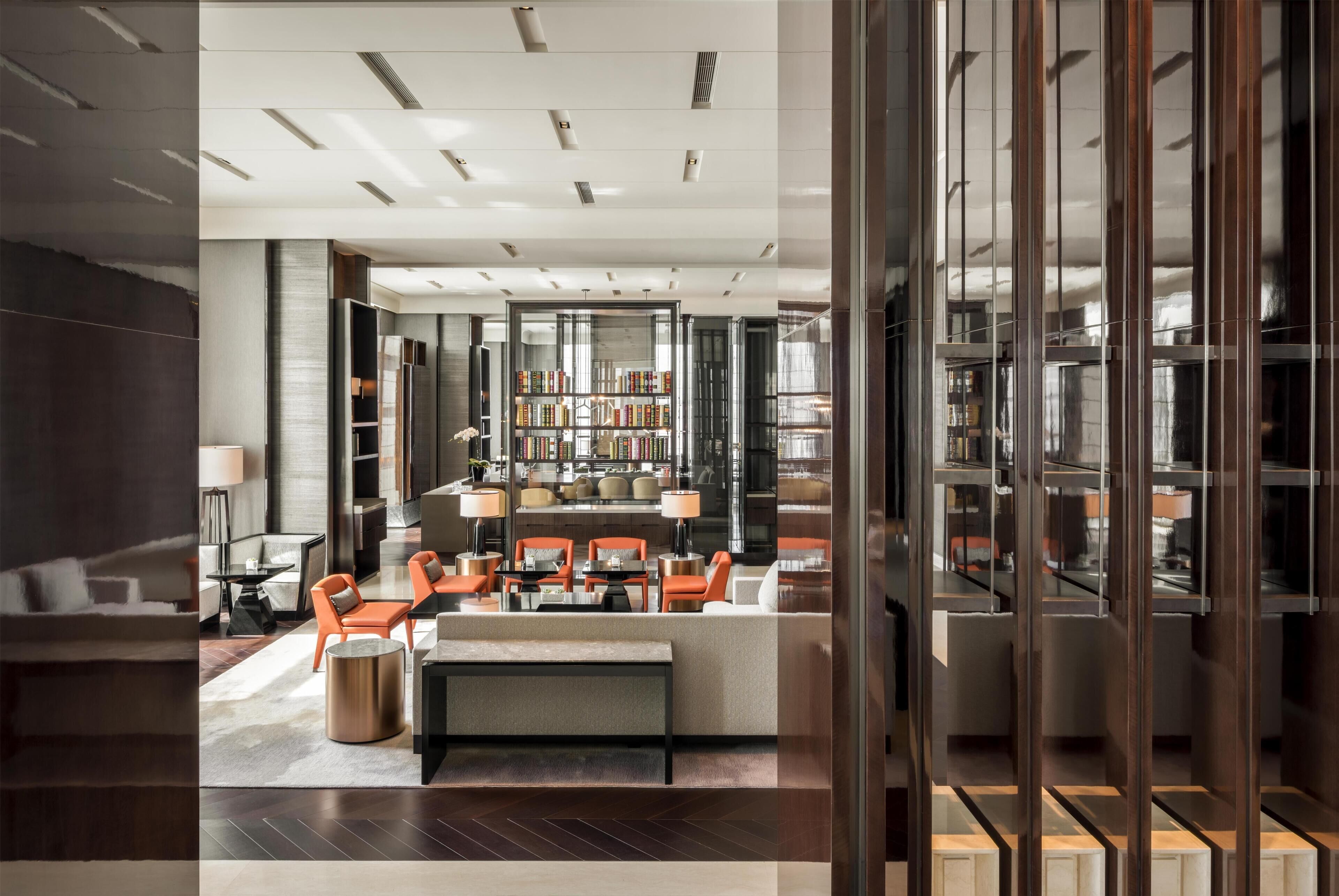 Une bibliothèque moderne dotée d’un espace de lecture central, d’étagères et d’une cloison en verre.