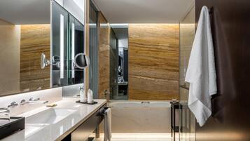 Un baño moderno con un espejo grande, lavamanos dobles, bañera y una toalla colgada en la pared.
