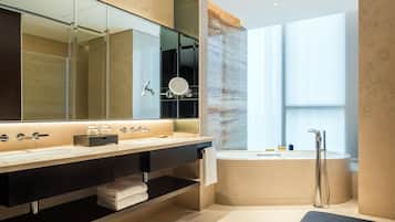 A modern bathroom with a large mirror, a bathtub, and a vanity with a sink.
