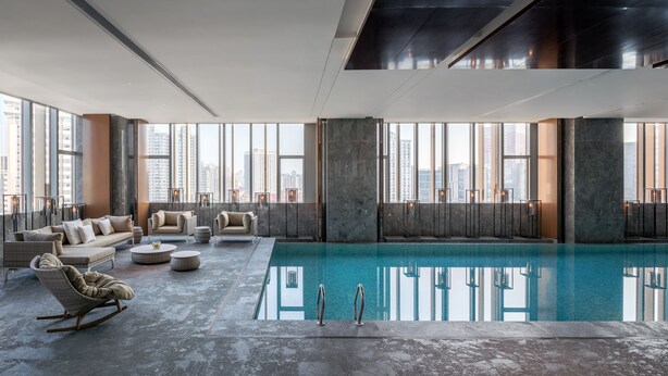 A spacious indoor pool area with a clear view of the city skyline through large windows. - Hyatt Regency Shanghai Global Harbor (Shanghai)