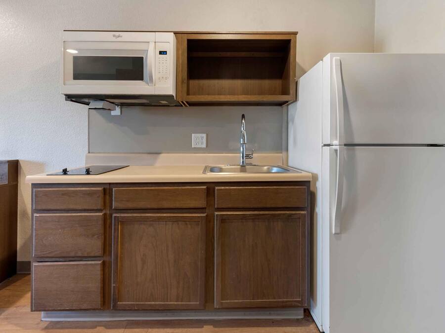 A compact kitchen with a built-in microwave, a sink, and a refrigerator.