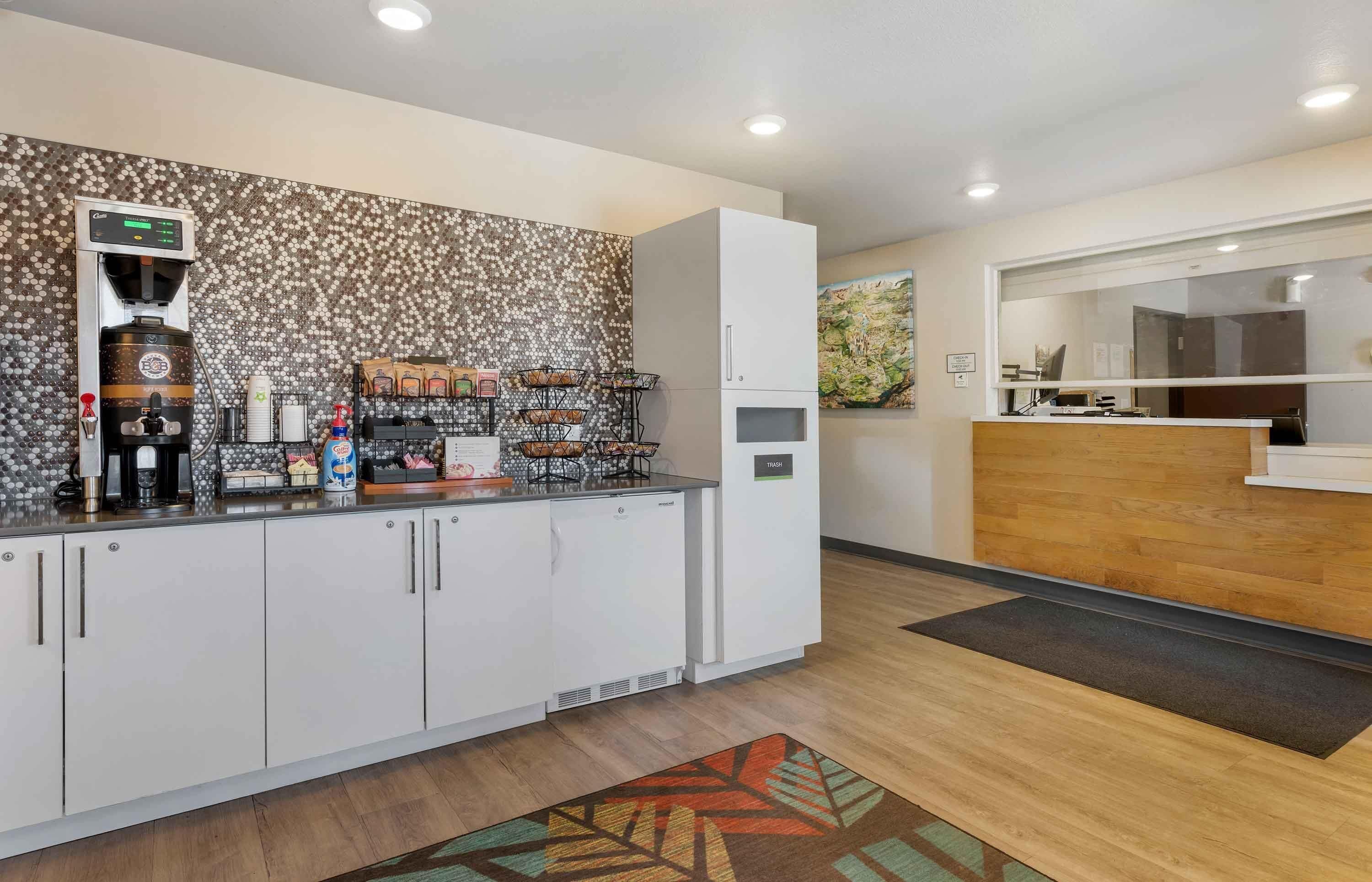 A modern kitchen with a coffee machine, a refrigerator, and a trash bin.