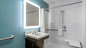 A bathroom with a white sink, a mirror, a shower with a handheld showerhead, and a towel rack.