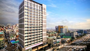 Un hotel di grandi dimensioni con numerosi piani, un cartello ben visibile e vista sullo skyline circostante.