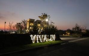 Un edificio con letreros iluminados que dicen "VIVALDI" al atardecer.
