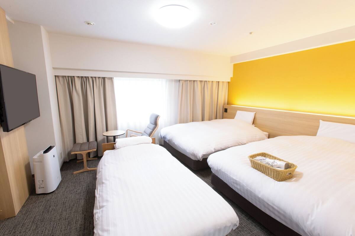 A hotel room with two beds, a TV, a desk, and a chair.