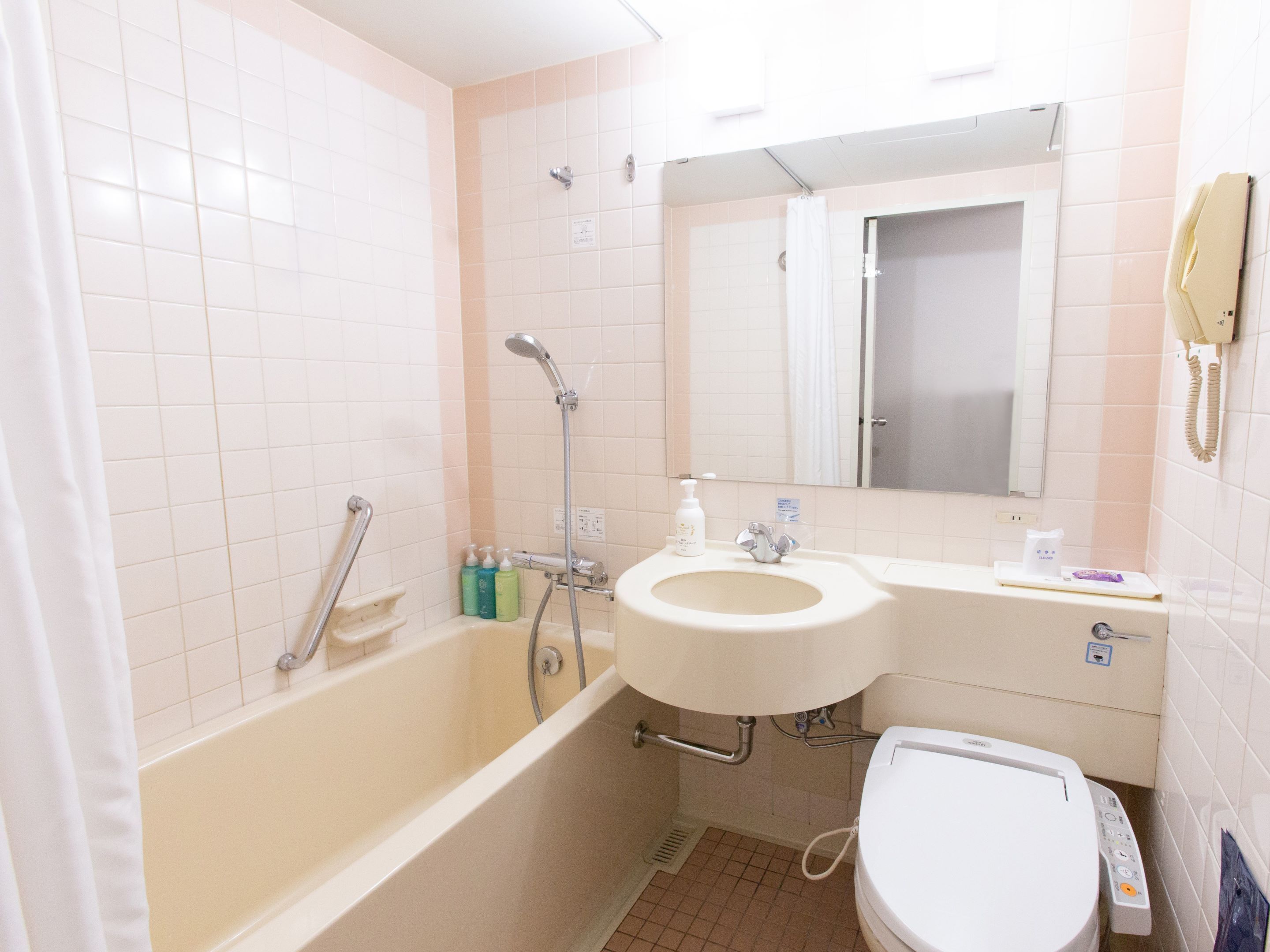 A bathroom with a bathtub, a sink, a toilet, and a mirror.
