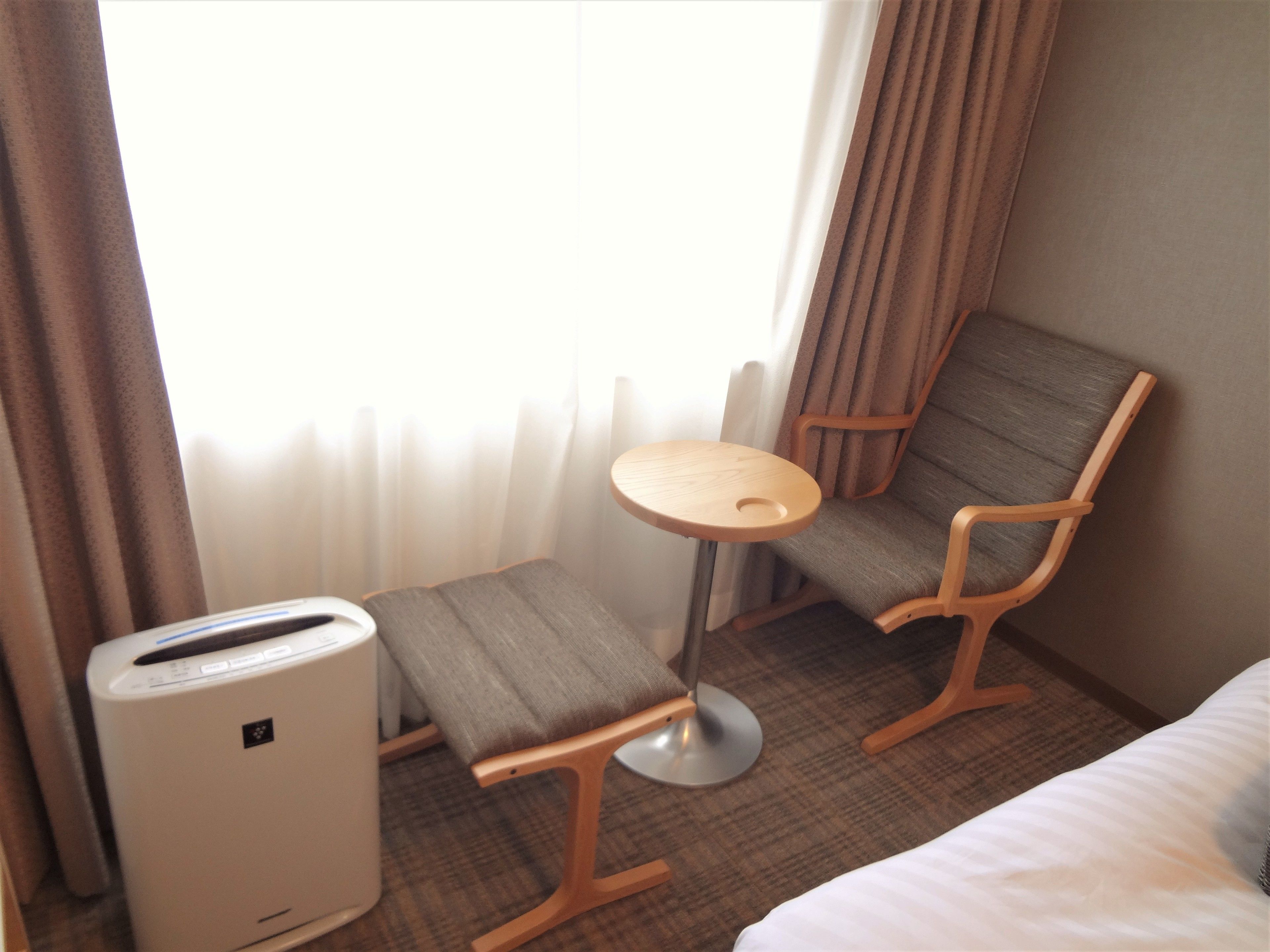 A hotel room with a bed, a small table, two chairs, and a heater.