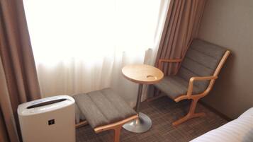 A hotel room with a bed, a small table, two chairs, and a heater.