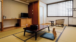 A traditional Japanese room with tatami flooring, a low table with a black container, a television on a wooden cabinet, and a large window with a grid pattern. - AMANOHASHIDATESOU (Miyazu)