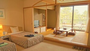 A hotel room with two beds, a desk, a chair, a television, and a balcony with a view of trees. - AMANOHASHIDATESOU (Miyazu)