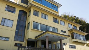 Ein mehrstöckiges Hotel mit gelber Fassade, großen Fenstern und einem überdachten Eingangsbereich.
