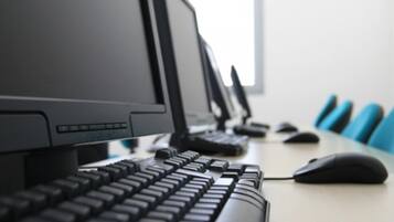 Eine Reihe von Computermonitoren auf einem Schreibtisch mit Tastatur und Maus.
