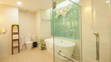 Een moderne badkamer met een douchecabine van glas, een witte badkuip en een toilet.