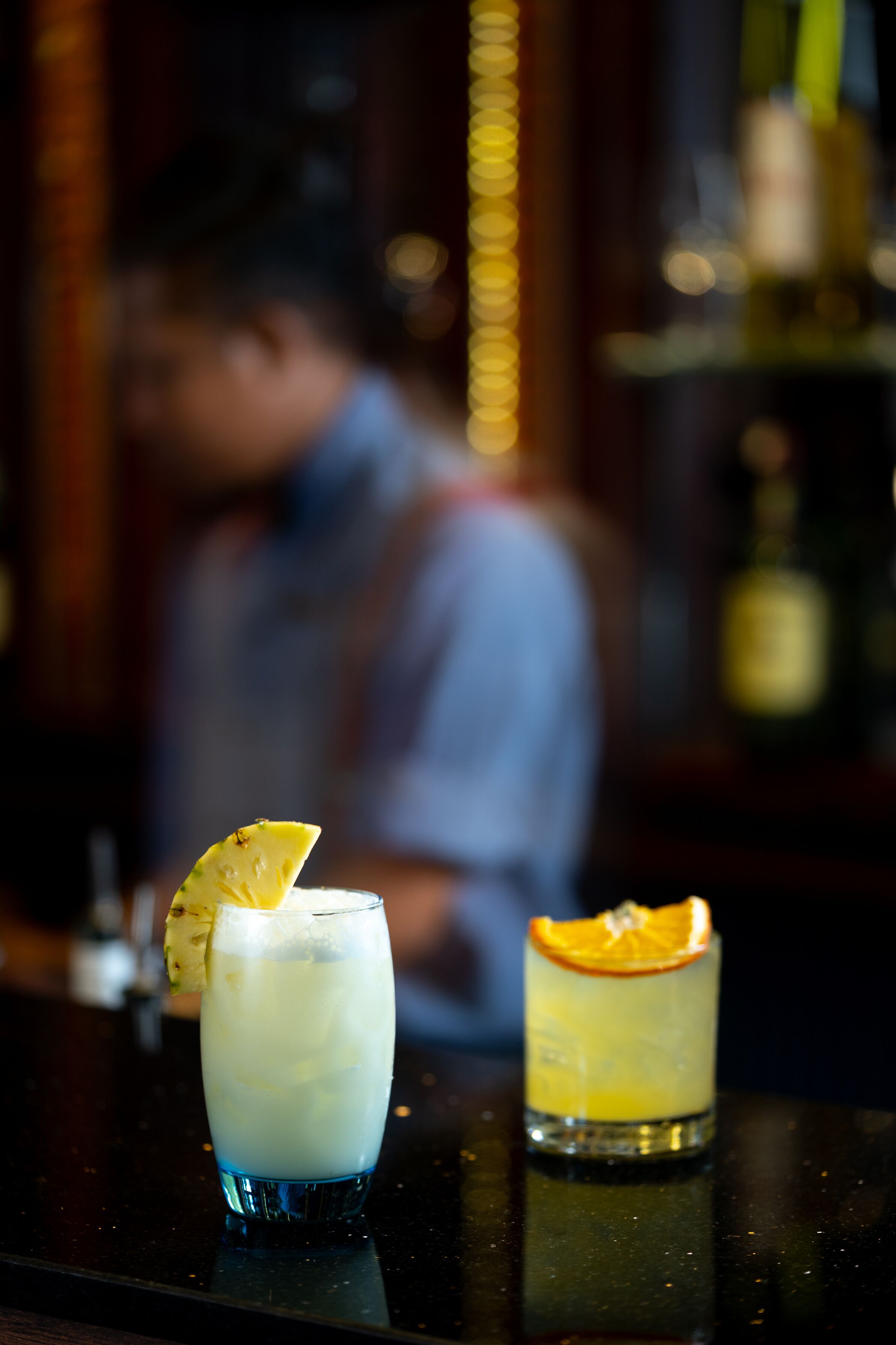 Un bar con una bebida adornada con una rodaja de naranja y un trozo de piña.