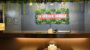 En receptionsdisk med en grøn væg og et skilt, der står 'OROX NAHA'.