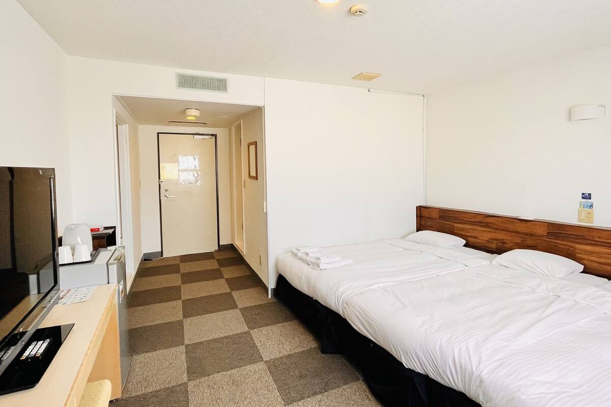 A hotel room with a bed, a TV, and a desk.