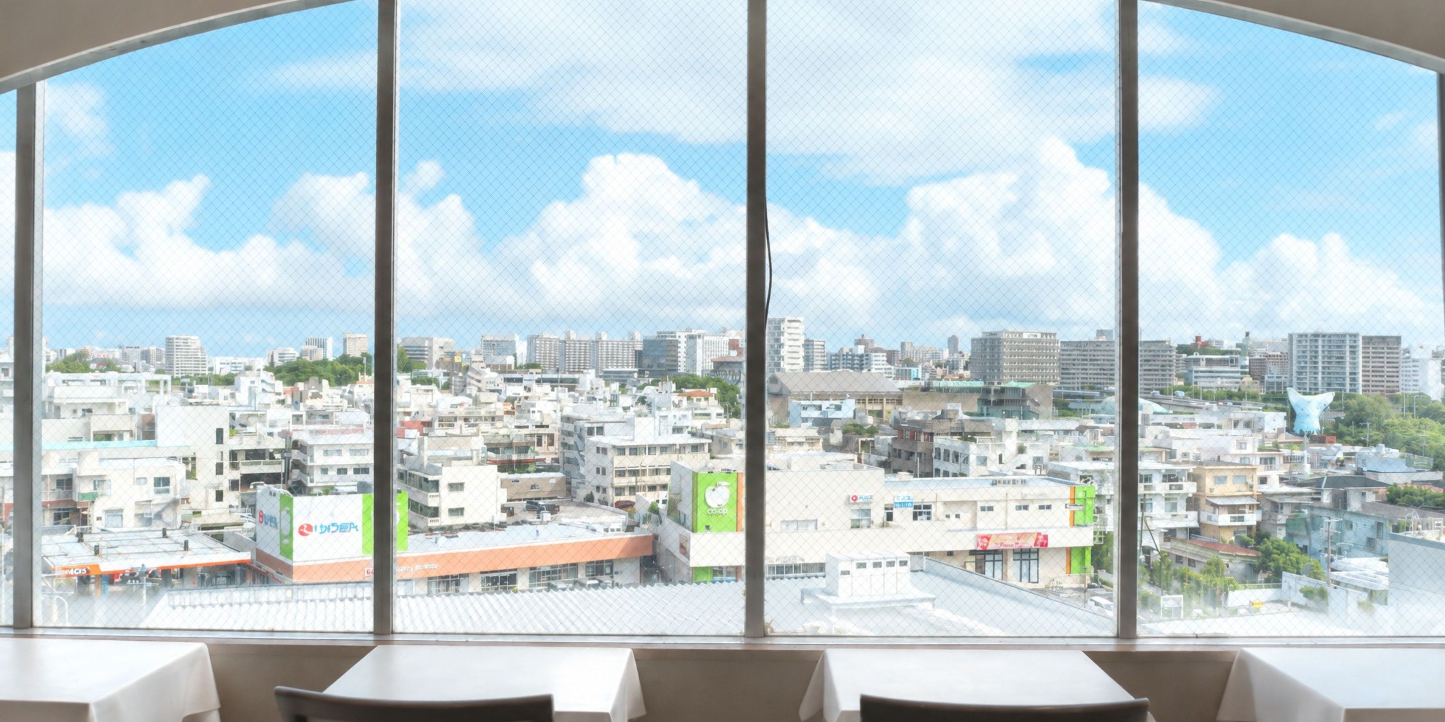A view from a room with a large window overlooking a cityscape with various buildings and a clear sky.